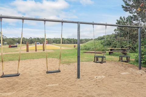 Parque infantil con columpios y suelo de arena en casa de vacaciones para 5 personas en Pandrup, Dinamarca.