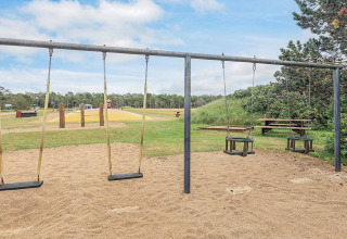 Parque infantil con columpios y suelo de arena en casa de vacaciones para 5 personas en Pandrup, Dinamarca.