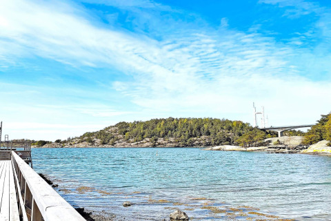 Vista su un lago tranquillo, isola boscosa, molo di legno e cielo blu vicino al sentiero Furufjall in Svezia.