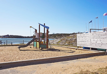 Parque infantil con estructura y tobogán en la arena junto al agua cerca del sendero Furufjall, Suecia.