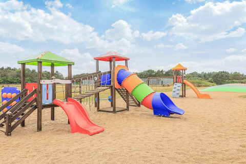 Parque infantil con toboganes y juegos de colores sobre arena en una casa vacacional en Pandrup, Dinamarca.
