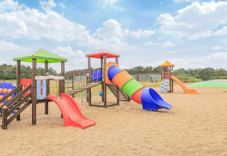 Parque infantil con toboganes y juegos de colores sobre arena en una casa vacacional en Pandrup, Dinamarca.