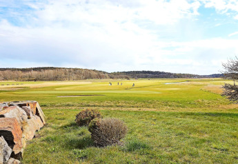Vista de un campo de golf verde con jugadores y cielo azul cerca del sendero Furufjall en Suecia.