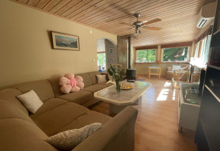 Salon d'une cabane paisible près du sentier Furufjall en Suède, avec canapé d'angle et grandes fenêtres lumineuses.
