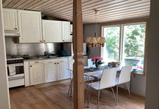 Lyst køkken og spisestue i en fredelig hytte nær Furufjall-stien i Sverige med udsigt til naturen.