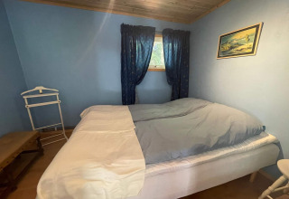 Dormitorio acogedor en la cabaña tranquila cerca del sendero Furufjall en Suecia, con paredes azules.