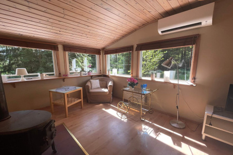 Lichte woonkamer in een vredige hut nabij het Furufjall-pad in Zweden, met grote ramen en gezellige inrichting.