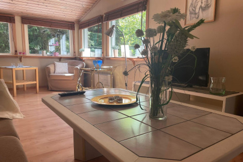 Soggiorno di una tranquilla baita vicino al sentiero Furufjall in Svezia, con ampie finestre e fiori freschi.