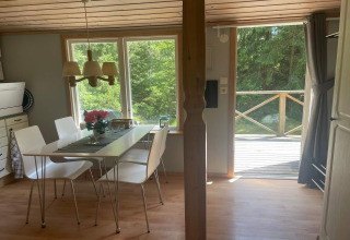 Comedor luminoso en una cabaña tranquila cerca del sendero Furufjall en Suecia, con vista al bosque.