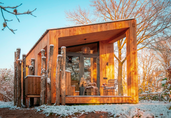Moderno chalet in legno Wellness Duynzicht a Sandberghe, Paesi Bassi, circondato da alberi innevati.