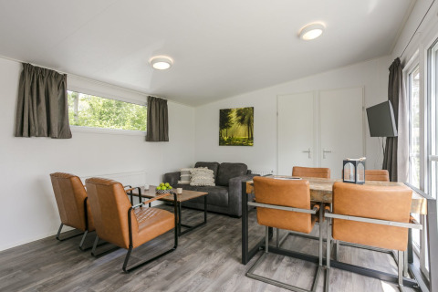 Living room inside Lodge Mistique at Holiday Park De Lochemse Berg featuring modern furniture and large windows.