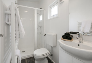 Moderne badkamer met douche, toilet en wastafel in Lodge Mistique op Holiday Park De Lochemse Berg, Nederland.
