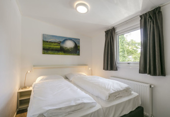 Slaapkamer van Lodge Mistique bij Holiday Park De Lochemse Berg in Nederland, met twee bedden en groot raam.