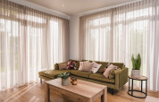 Soggiorno moderno in una luxury lodge a Vakantiepark Hölte, Paesi Bassi, con divano verde e grandi finestre.