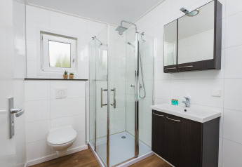 Moderne badkamer met glazen douche, hangtoilet en wastafel in Luxury Lodge op Vakantiepark Hölte.