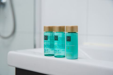 Drie groene Rituals of Karma flesjes op een wit badmeubel in de Luxury lodge van Vakantiepark Hölte.