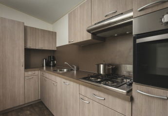 Moderne keuken met lichte houten kasten, gaskookplaat en oven in Cosy cabin bij Vakantiepark Hölte.