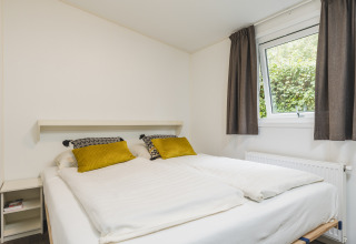 Cozy bedroom in a cabin at Vakantiepark Hölte, Netherlands, with comfy bed, window, and bright décor.