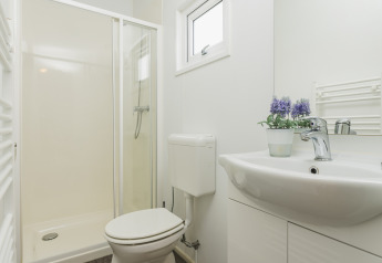 Moderne badeværelse i en hytte på Vakantiepark Hölte i Holland med brus, toilet, vask og vindue.