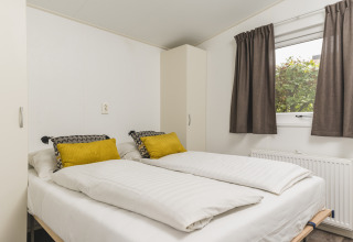 Dormitorio de Cosy cabin en Vakantiepark Hölte, Países Bajos, con dos camas individuales y ventanales.