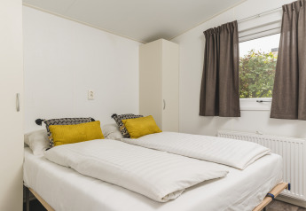 Slaapkamer in Cosy cabin bij Vakantiepark Hölte in Nederland, met twee eenpersoonsbedden en raam.