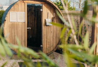 Udendørs tøndesauna ved Veluwe lounge + sauna, Holiday park De Boshoek, Holland, omgivet af grønne planter.