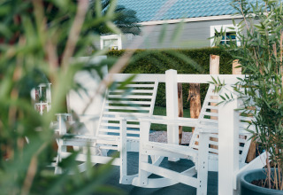 Panchine bianche e piante verdi al Veluwe lounge + sauna presso Holiday park De Boshoek, Paesi Bassi.