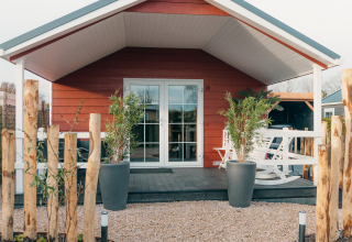 Rode lodge met veranda en planten, Veluwe lounge + sauna bij Vakantiepark De Boshoek in Nederland.