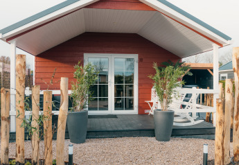 Chalet rouge avec véranda et plantes, Veluwe lounge + sauna au parc de vacances De Boshoek, Pays-Bas.