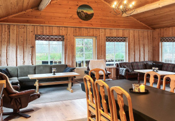 Séjour chaleureux au lodge Trollhytta au Danemark avec intérieur en bois, canapés et grandes fenêtres.