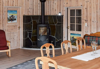Salon chaleureux du lodge Trollhytta au Danemark avec poêle à bois, murs en bois et ambiance rustique.