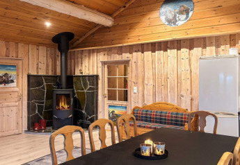 Salon chaleureux à Trollhytta, avec poêle à bois, murs en bois, canapé écossais et bougies décoratives.