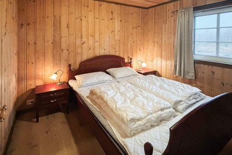 Soveværelse i lodge 76409 TROLLHYTTA, Danmark, med træpanelvægge, dobbeltseng og vindue.