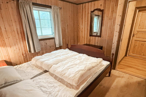 Soveværelse i lodge '76409 TROLLHYTTA' i Danmark med trævægge, dobbeltseng og vindue.
