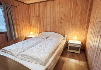 Chambre de la lodge 76409 TROLLHYTTA au Danemark avec lit double, murs en bois et lampes de chevet.