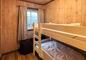 Chambre chaleureuse avec lits superposés, boiseries et rideaux à la cabane 76409 TROLLHYTTA au Danemark.