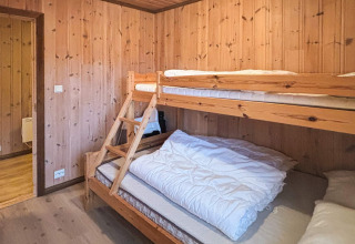 Værelse med køjeseng i træ og lyse trævægge på TROLLHYTTA lodge i Danmark, hyggelig atmosfære.