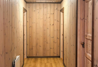 Gang med træpaneler og døre i en lodge kaldet 76409 TROLLHYTTA, taget i Danmark.