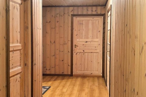 Træbeklædt gang på lodge 76409 TROLLHYTTA i Danmark med naturlige træpaneler og døre.