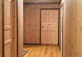 Træbeklædt gang på lodge 76409 TROLLHYTTA i Danmark med naturlige træpaneler og døre.