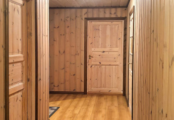 Couloir lambrissé de bois au lodge 76409 TROLLHYTTA au Danemark, avec portes et sols en bois naturel.
