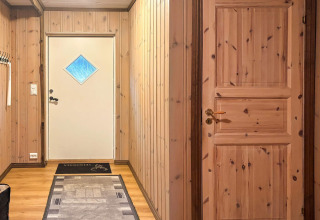 Indgangsparti i lodge '76409 TROLLHYTTA' i Danmark med træpanelvægge, to døre og tæpper.