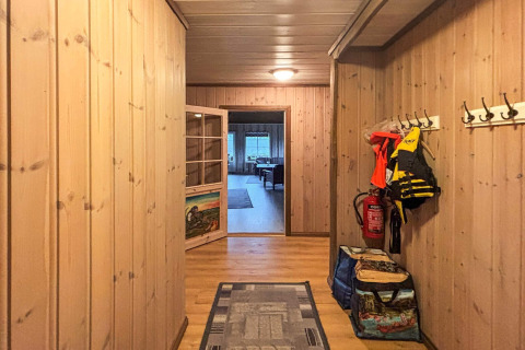 Indgang i lodge med træpaneler, jakker, redningsveste og brandslukker på væggen i Danmark.