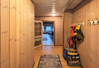Couloir d’un lodge aux murs en bois, vestes, gilets de sauvetage et extincteur au Danemark.
