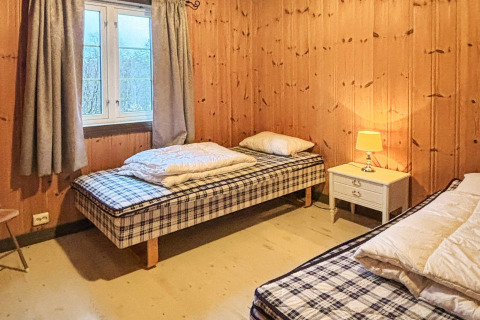 Et hyggeligt soveværelse på 76409 TROLLHYTTA i Danmark med to enkeltsenge, træpaneler og natbord.