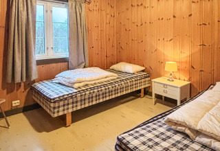 Et hyggeligt soveværelse på 76409 TROLLHYTTA i Danmark med to enkeltsenge, træpaneler og natbord.