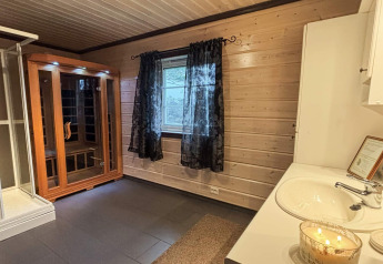 Salle de bain moderne avec sauna, douche et lavabo au lodge 76409 TROLLHYTTA au Danemark.