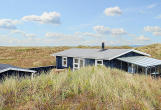 Casa de campo Seaside Bliss en albaek, Dinamarca, rodeada de dunas y naturaleza bajo cielo azul.