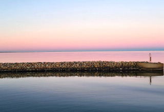 Steinmauer am Wasser bei Sonnenuntergang, Seaside Bliss in albaek, Dänemark, mit rosa-blauem Himmel.