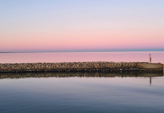 Stenen muur aan het water bij zonsondergang en roze-blauwe lucht, Seaside Bliss in albaek, Denemarken.